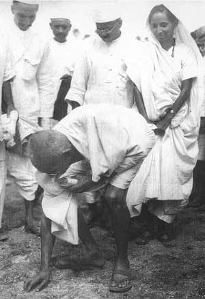 Gandhi ramassant la poignée de sable
